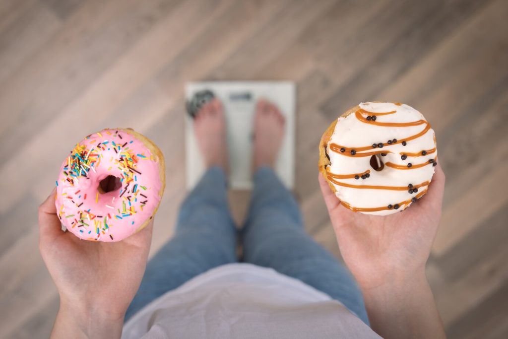 mulher segurando duas rosquinhas, sendo uma em cada mão